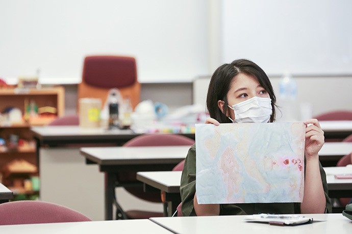 振り返りの時間、草木で染めた作品を掲げるゼミ生の高木美和さん(写真/朝日新聞出版写真部・張溢文)