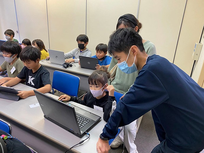 「CoderDojo Ishigaki」で、小学生にヒントを伝えている一さん